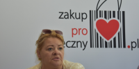 kobieta na tle plakatu promującego "Zakup Prospołeczny"
