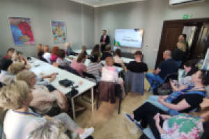 ludzie siedzą przy stołach podczas prezentacji