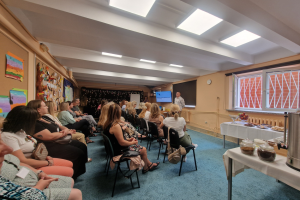 grupa ludzi siedzi słuchając wykładu