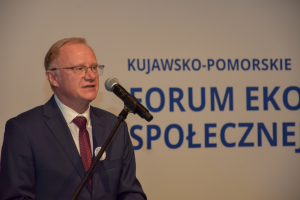 mężczyzna w garniturze stoi przed mikrofonem