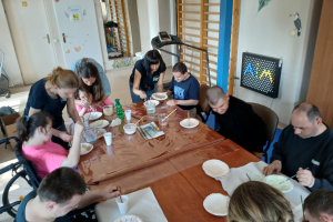 grupa ludzi przy stole podczas wykonywania prac plastycznych