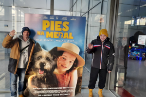 mężczyźni stoją obok plakatu filmowego