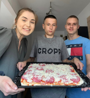 grupa ludzi prezentuje pizzę