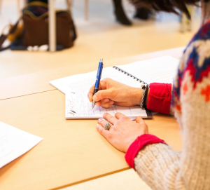 dłonie trzymają długopis i piszą w notesie