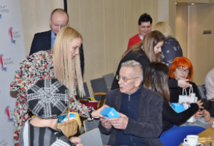 grupa ludzi wśród nich kobieta z tarczą na berecie