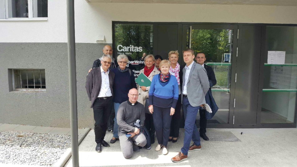 grupa ludzi stoi przed wejściem do budynku