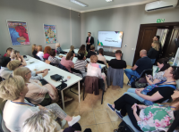 ludzie siedzą przy stołach podczas prezentacji