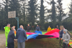 ludzie stoją w okręgu dookoła kolorowej chusty