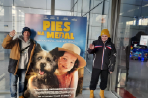 mężczyźni stoją obok plakatu filmowego