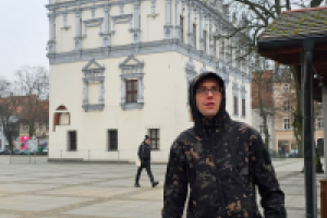 mężczyzna stoi na tle budynku z wieżą zegarową