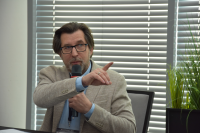 mężczyzna w okularach trzyma mikrofon i wskazuje palcem