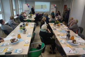 mężczyzna przemawia, ludzie siedzą przy stołach