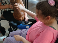 kobieta na wózku inwalidzkim głaszcze psa