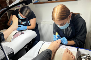 dwie kobiety wykonują pedicure