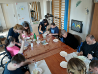 grupa ludzi przy stole podczas wykonywania prac plastycznych