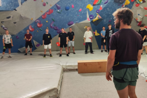 ludzie stoją przy ściance wspinaczkowej