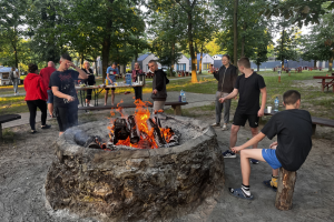 ludzie stoją przy ognisku