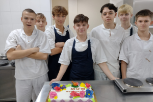 grupa młodych mężczyzn stoi przy torcie