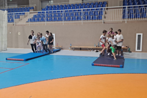 grupa dzieci stoi na materacach w sali gimnastycznej