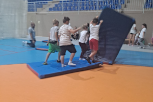 grupa dzieci z materacami w sali gimnastycznej