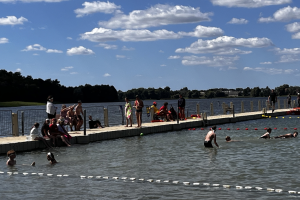 ludzie siedzą na pomości nad jeziorem