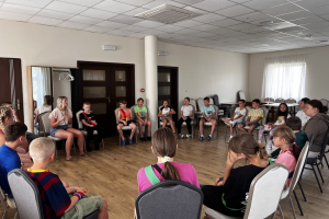 gruoa dzieci siedzi w kółku na krzesłach