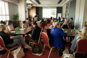 ludzie siedzą na krzesłach przy stołach